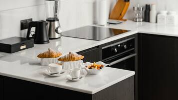 Une cuisine moderne dotée d’un plan de travail blanc, d’une machine à café, d’un mixeur et d’un bloc à couteaux.