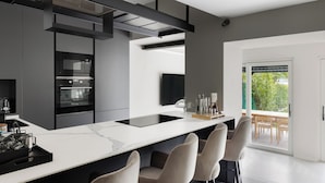 Una cocina moderna con una isla grande, electrodomésticos integrados y vistas al exterior.