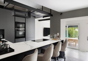 Una cocina moderna con una isla grande, electrodomésticos integrados y vistas al exterior.