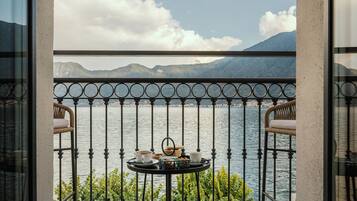 Ein Balkon mit Tisch für zwei Personen, mit Blick auf ein Gewässer und Berge.