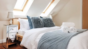 A bedroom with a skylight, a bed with white bedding, a grey blanket, and a nightstand with a lamp. - Greenknowes Entire Private Estate (Blairadam)