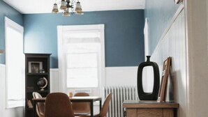 A dining area with a wooden table and chairs, a chandelier, and a radiator. - 2-bedroom apartment in Portland, ME with WiFi, AC. Enjoy your stay! (Portland)