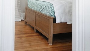 A bedroom with a wooden bed, a white wall, and a ceiling with a grid pattern. - 2-bedroom apartment in Portland, ME with WiFi, AC. Enjoy your stay! (Portland)