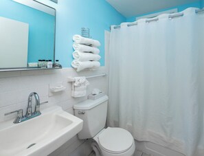 Bañera con ducha, toallas, papel higiénico