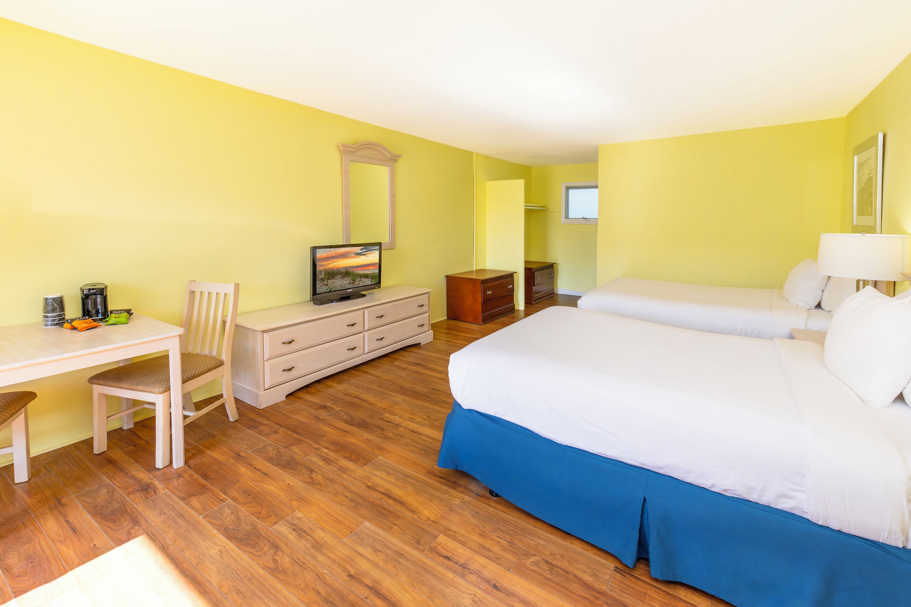 Una habitació d'hotel amb un llit, un escriptori amb una cadira, un taulell de vestir i una televisió.