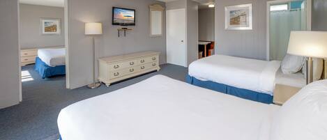 A hotel room with two beds, a dresser, a television, and a mirror.
