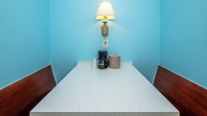 A room with a white countertop, a coffee maker, a lamp, and a trash bin against a blue wall. - The Beach House at Drifting Sands (Beach Haven)