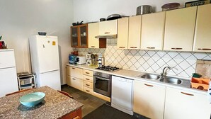 A compact kitchen with white cabinets, a gas stove, a sink, and a refrigerator. - Villa da Anna e Turi - a 5 minuti dal mare (Budoni)