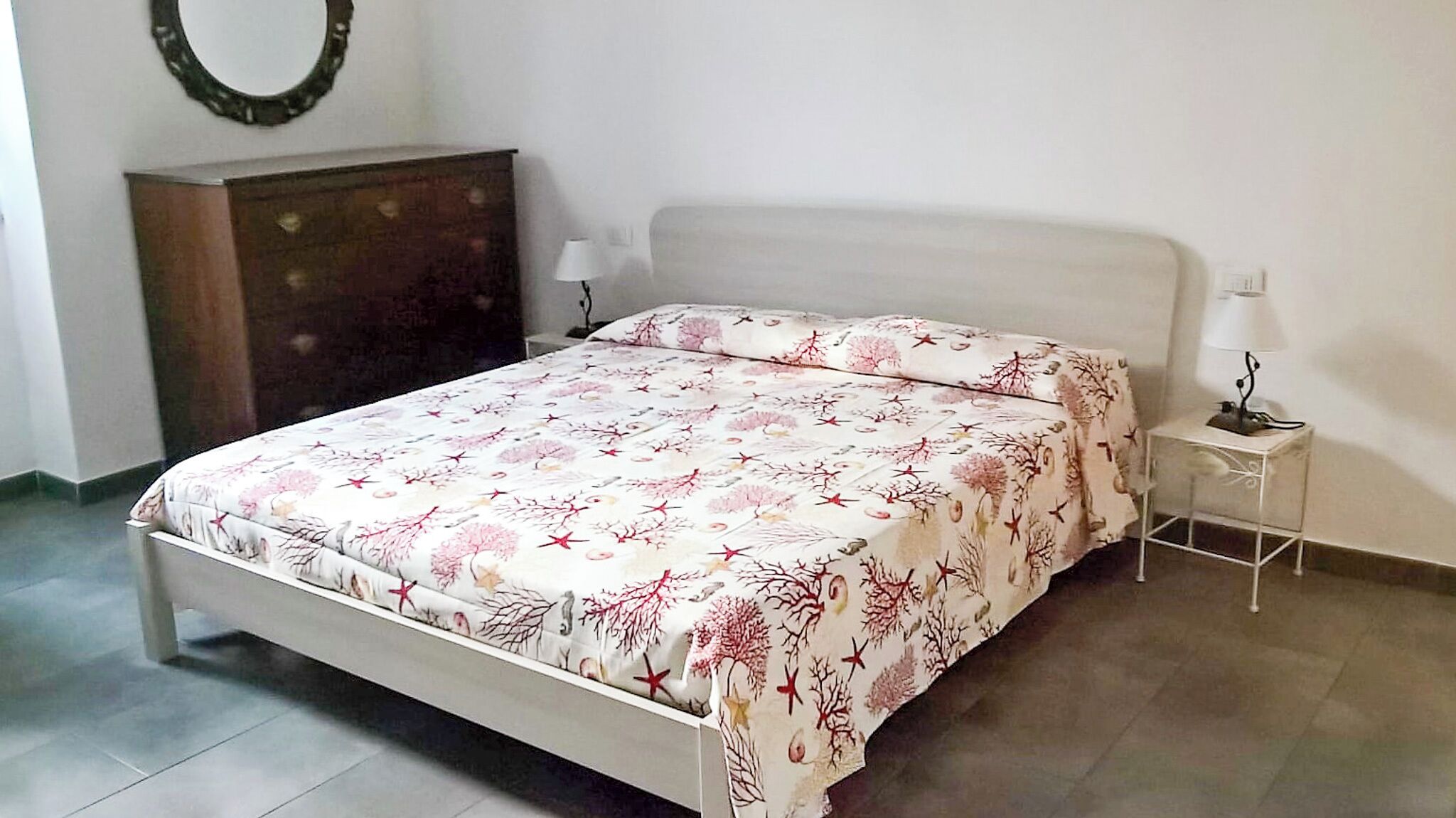 Ein Schlafzimmer mit Bett, Nachttisch, Kommode und einem Wandspiegel.