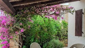 A covered outdoor seating area with stone flooring, wicker chairs, and a table with papers and a smartphone. - Villa da Anna e Turi - a 5 minuti dal mare (Budoni)