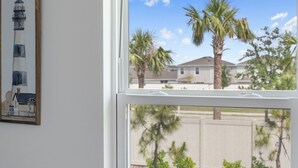 Ein Fenster mit Blick auf eine Wohngegend, darunter Palmen und ein Haus.