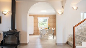 A modern interior with a fireplace, dining area, and staircase.