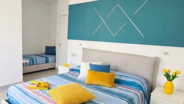 Ein modernes Schlafzimmer mit einem großen Bett, einem Nachttisch und einer Wandleuchte.