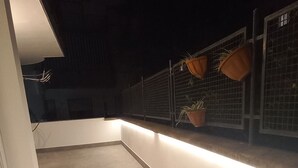Ein schwach beleuchteter Korridor mit Fliesenboden, weißer Wand und hängenden Pflanzen.