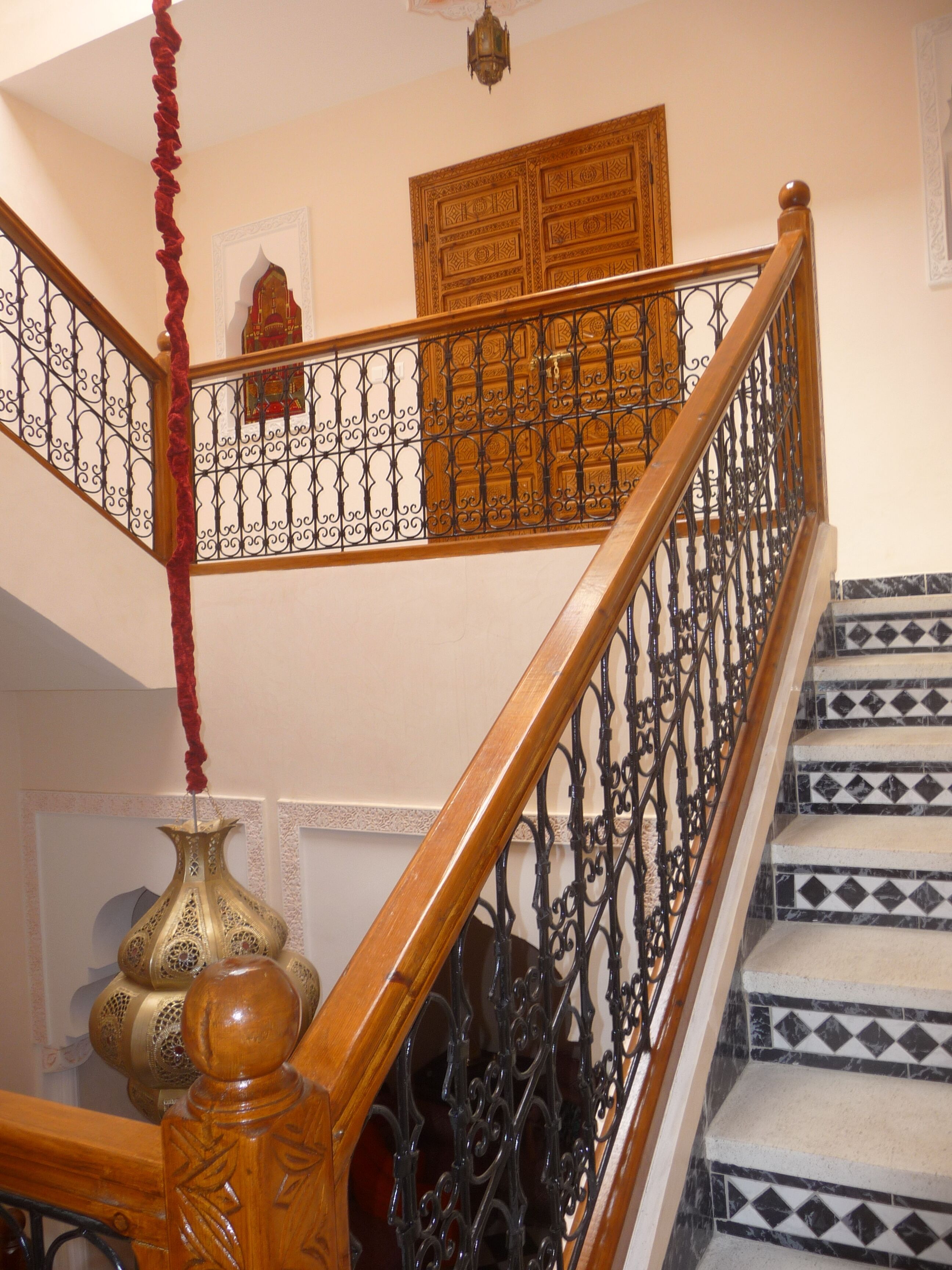 Un escalier orné de rampes en fer forgé noir et d’une main courante en bois.