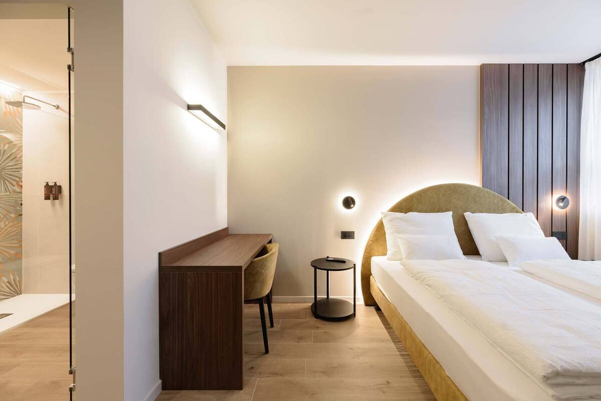 Une chambre d’hôtel moderne équipée d’un lit, d’une table de chevet, d’une chaise et d’un bureau.
