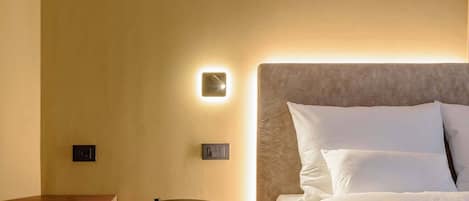 A hotel room with a bed, bedside tables, and a wall-mounted light fixture.