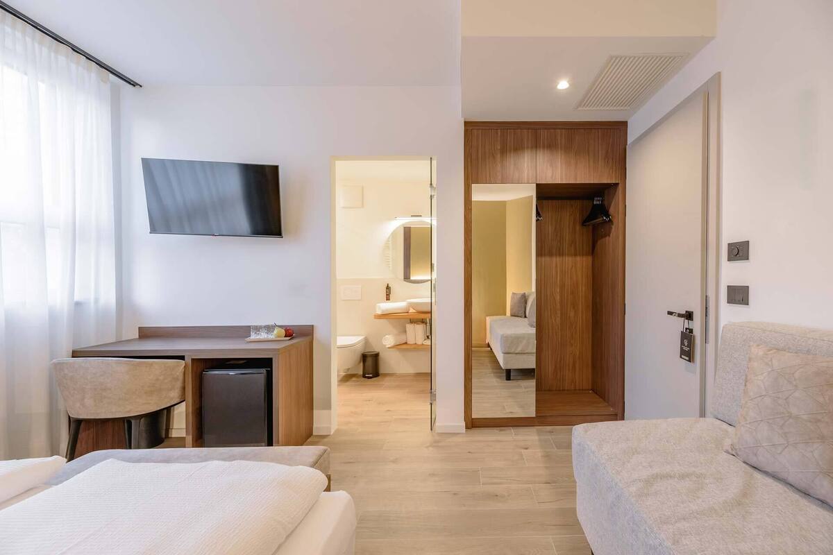 Une chambre d’hôtel comprenant un lit, un bureau, une télévision, une salle de bain avec douche et une armoire en bois.