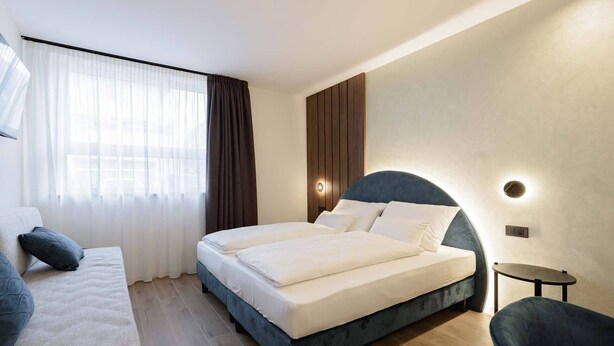 Ein modernes Hotelzimmer mit einem großen Bett, einer Couch und einem kleinen Tisch.