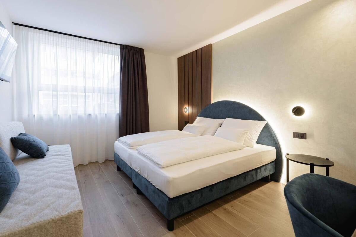 Une chambre d’hôtel moderne avec un grand lit, un canapé et une petite table.