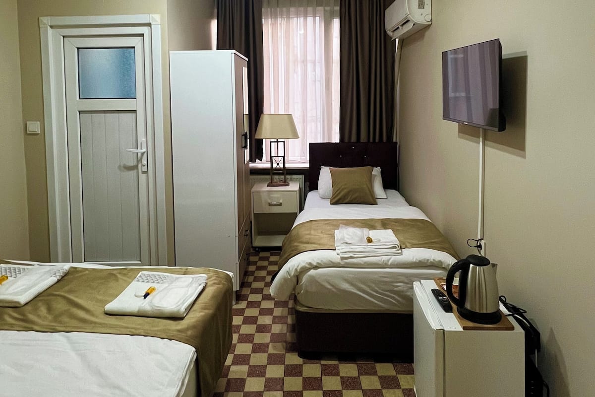 A hotel room with two beds, a television, a desk, a lamp, and a ceiling fan.
