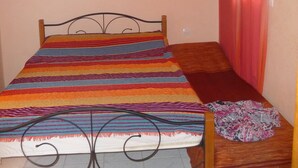 A single bed with a metal frame, a colorful striped bedspread, and a red curtain. - MARRAKECH RYAD ALL COMFORTS IN A RESIDENCE WITH 3 LARGE SWIMMING POOLS (Marrakech)