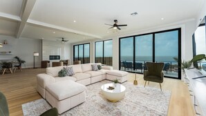 Ein modernes Wohnzimmer mit einer großen Eckcouch, einem Couchtisch und Meerblick durch große Fenster.