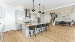 Eine moderne Küche mit Kochinsel, Barhocker und Essbereich mit Treppe.