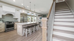 A modern kitchen with a central island, stainless steel appliances, and bar stools.