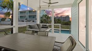 A covered outdoor area with a pool, a dining table, and a sofa.