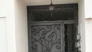 A grey metal gate with intricate scrollwork, a small light fixture above, and a power outlet on the right. - Furlong1 Apartment in down Town city near the malecón and restaurants (La Paz)