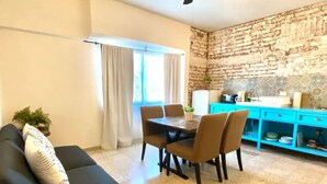 A living room with a dark-colored sofa, a dining table with chairs, a ceiling fan, and a kitchen area with blue cabinets. - Furlong1 Apartment in down Town city near the malecón and restaurants (La Paz)