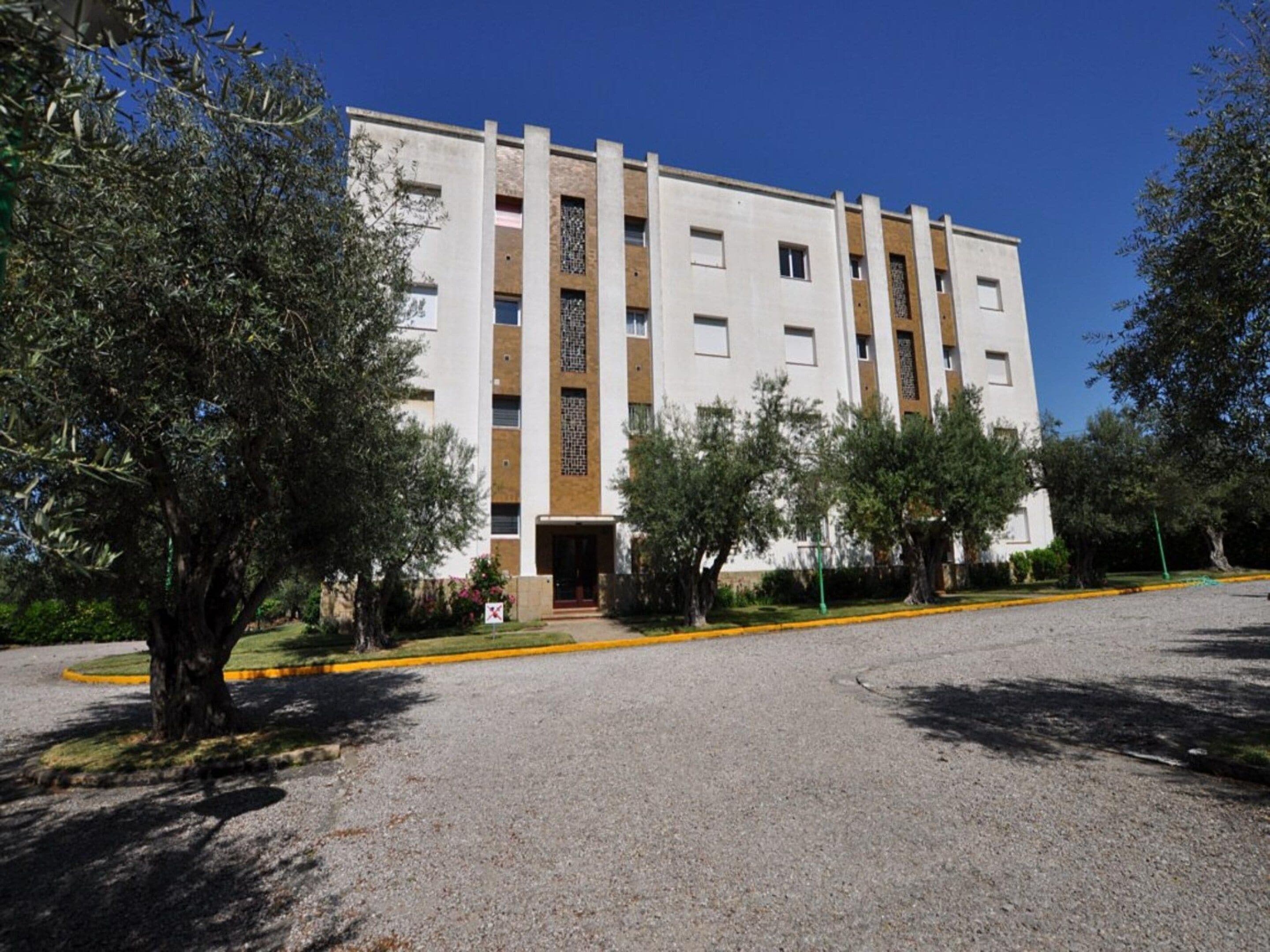 Un edificio de varios pisos con fachada simétrica, una entrada central y un camino de grava.