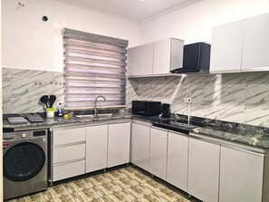 Une cuisine compacte équipée d’un lave-linge, d’un four à micro-ondes et d’une machine à café.