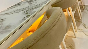 Une longue table à manger avec un plateau en marbre, entourée de chaises rembourrées dotées d’accoudoirs.