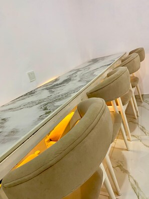 A long dining table with a marble top, surrounded by cushioned chairs with armrests. - Lux 3BD/3BA Flat | Parkview Ikoyi | NG01 (Lagos)