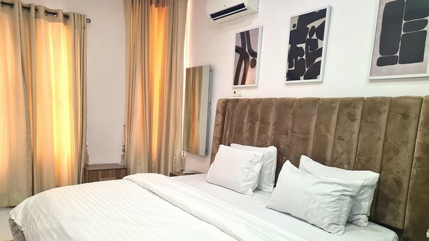 Une chambre d’hôtel avec un grand lit, une tête de lit, une table de chevet et un climatiseur fixé au mur.
