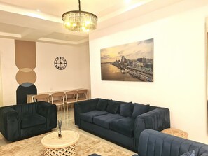 Un salon moderne avec des canapés bleu foncé, une table basse ronde et un lustre.