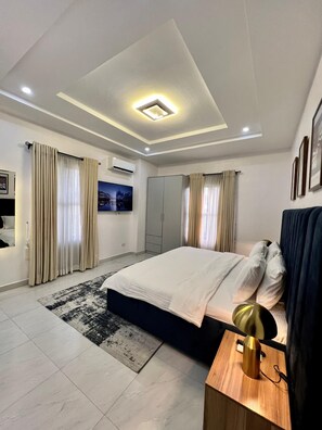 A modern bedroom with a large bed, a bedside table, a wardrobe, and a ceiling light fixture. - Lux 3BD/3BA Flat | Parkview Ikoyi | NG01 (Lagos)