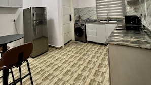 Une cuisine compacte équipée d’un réfrigérateur, d’un lave-linge et d’un évier.