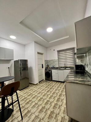 A compact kitchen with a refrigerator, washing machine, and a sink. - Lux 3BD/3BA Flat | Parkview Ikoyi | NG01 (Lagos)