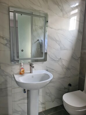 A bathroom with a white sink, a mirror above it, and a toilet. - Lux 3BD/3BA Flat | Parkview Ikoyi | NG01 (Lagos)