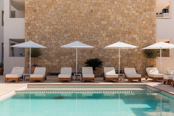 Una piscina al aire libre de temporada, sombrillas, tumbonas
