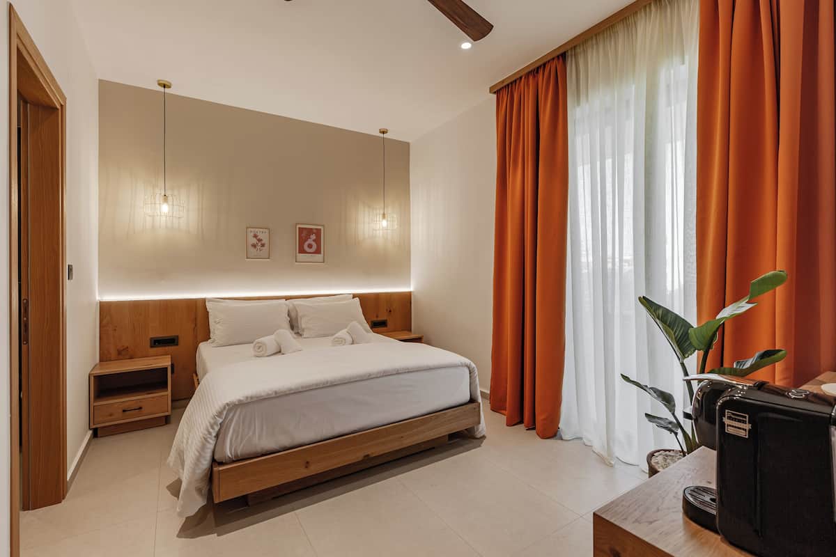 A modern bedroom with a wooden bed, bedside tables, a ceiling fan, and a large window with orange curtains.