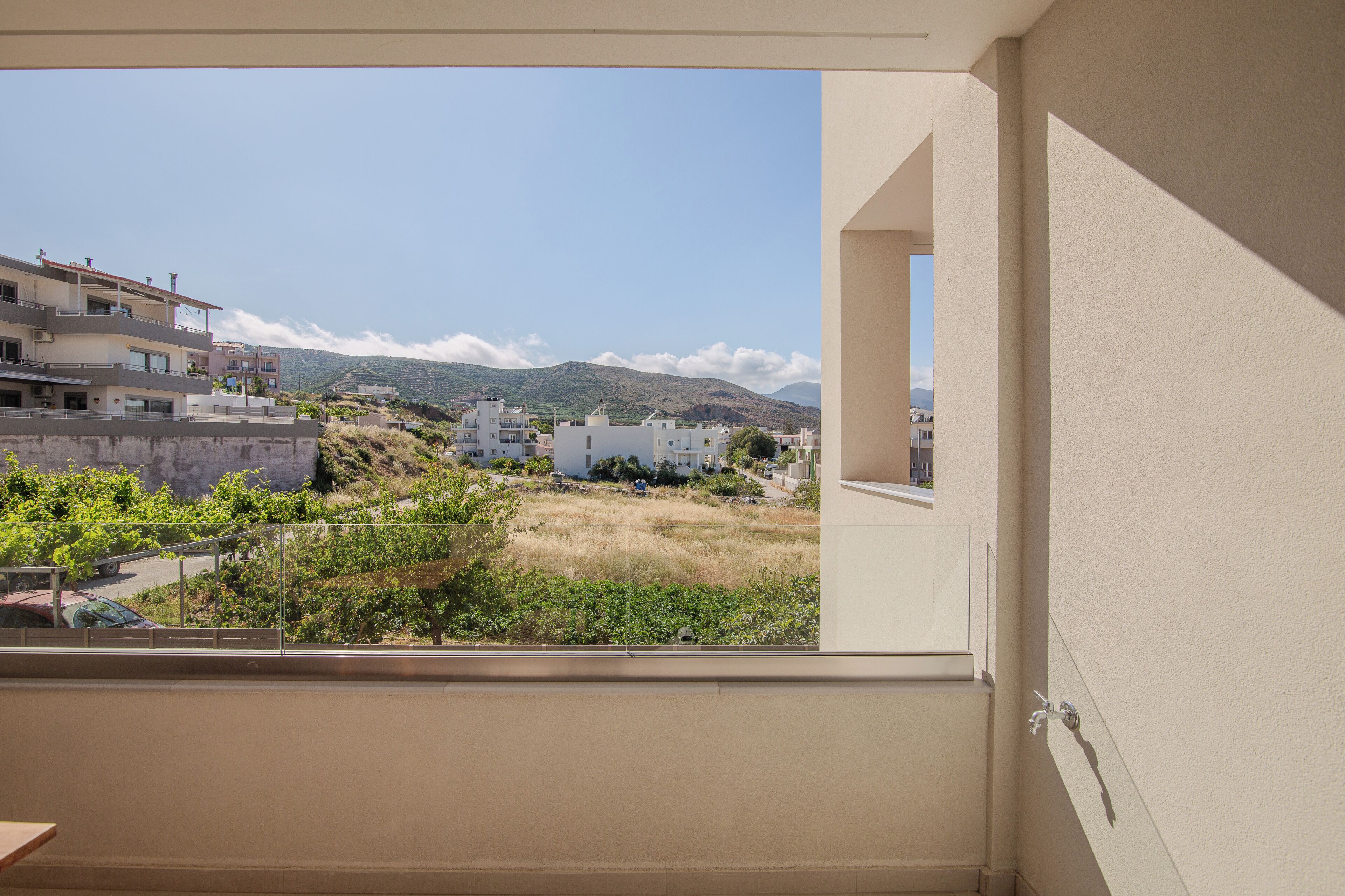 Un balcon donnant sur un quartier résidentiel, avec des maisons et une montagne visible au loin.