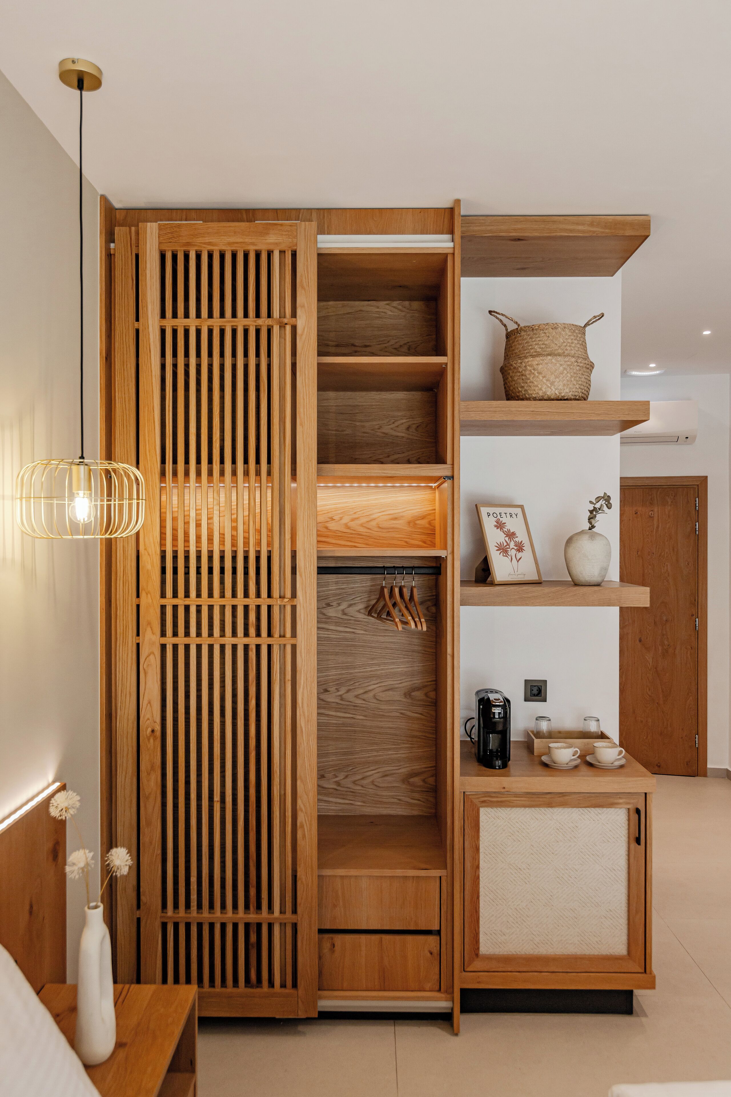 A modern interior with a wooden cabinet, a hanging light fixture, and a shelf with decorative items.