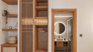 A modern bathroom with a wooden vanity, a round mirror, and a glass shower enclosure. - Sarana Suites Crete  (Kissamos)