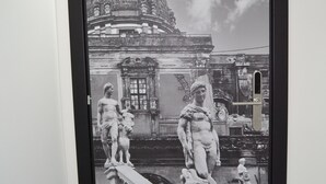 A black and white photograph of a grand building with a dome and statues, framed and hung on a wall.
