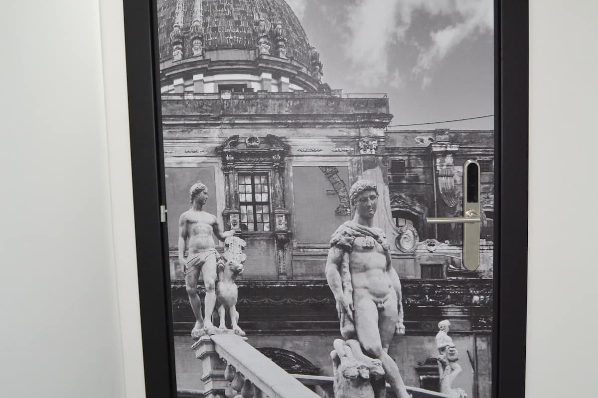 A black and white photograph of a grand building with a dome and statues, framed and hung on a wall.