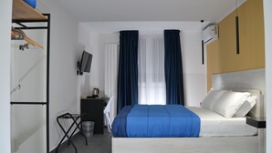 A bedroom with a bed, a desk, a chair, a TV, and a wardrobe.